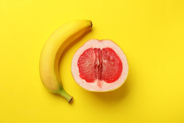 Banana and half of grapefruit on yellow background, flat lay. Sex concept