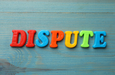Word Dispute made of colorful letters on light blue wooden table, flat lay