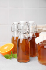 Tasty kombucha, orange and mint on white table