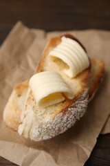Tasty butter curls and slices of bread on wooden table, closeup