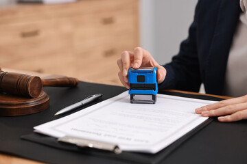Notary stamping document at table in office, closeup