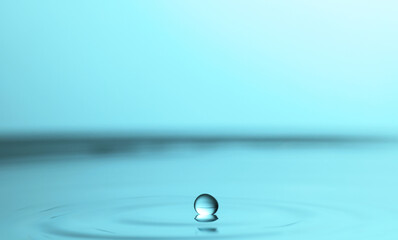 Splash of clear water with drop on turquoise background, closeup
