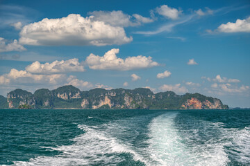 Tropical islands view behind speed boat with ocean blue sea water and white sand beach at Railay...