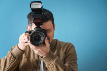Male photographer with professional camera on blue background