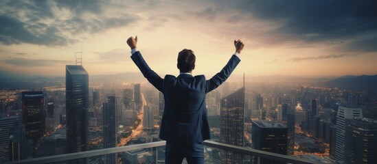 Fototapeta na wymiar Businessman with arms raised celebrating success on standing in front of modern high-rise city