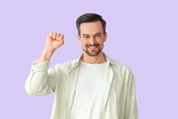 Handsome man with clenched fist on lilac background