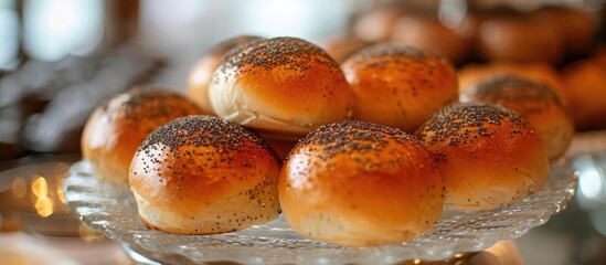 A detailed view of a plate filled with poppy seed bread rolls on a glass buffet table.