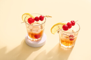 Glasses of tasty cocktail with maraschino cherries on yellow background