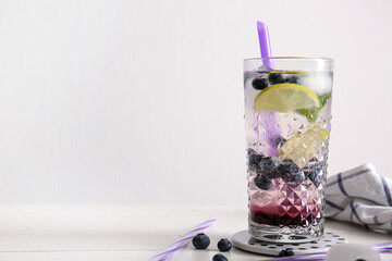 Glass of fresh blueberry lemonade on white wooden table