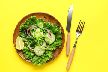 Plate of tasty vegetable salad on yellow background