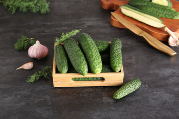 Wooden box with fresh cucumbers on black background