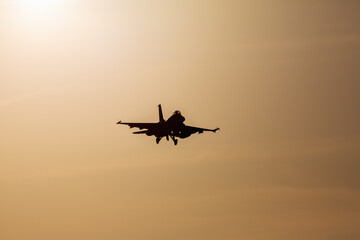 Fototapeta na wymiar 夕日を浴びて映画のような着陸するF-2戦闘機のシルエット
