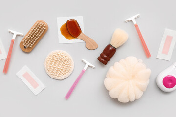 Different supplies for hair removal with sponge and brushes on grey background