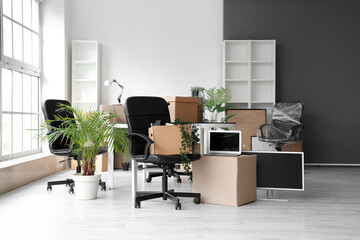 Interior of modern office with chairs, houseplants and cardboard boxes on moving day