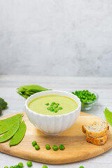 Cream soup with green peas on white wooden table. Healthy, diet food. Vegetarian food. 