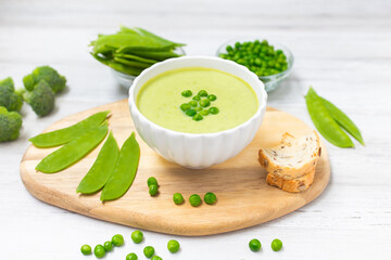 Cream soup with green peas on white wooden table. Healthy, diet food. Vegetarian food. 