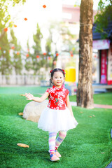A cute little Thai girl wearing a red Chinese traditional dress.