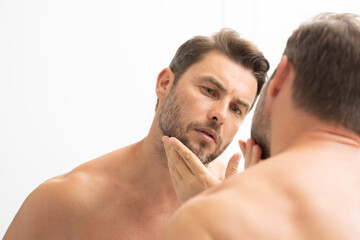 sexy man with stubble looks at the wrinkles on his face. Close up man looking in mirror, sensitive...