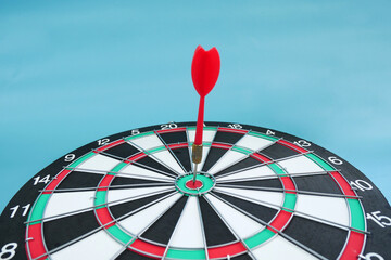 Red darts in the dartboard center target on a blue background. Business target concept or goal...