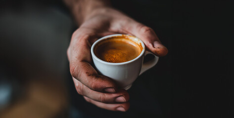 A close-up of a hand holding a cup of coffee, representing the importance of caffeine in the business world realistic photography
