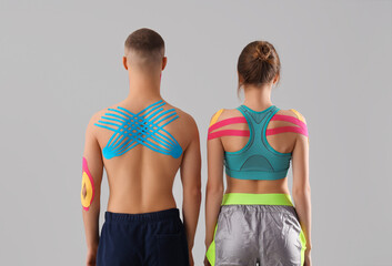 Young couple with physio tape on grey background, back view