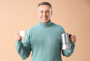 Mature man with geyser coffee maker and cup on beige background
