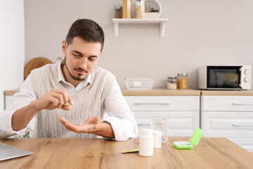Young man counting pills at home