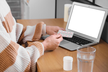 Young man checking pills description online at home, closeup
