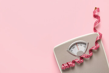 Scales with pink measuring tape on color background