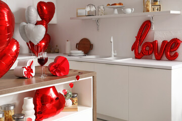Glasses of wine with gifts on table in kitchen decorated for Valentine's Day