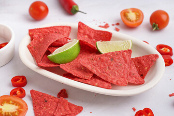 Plate with red nachos, lime and chilli on white background, closeup