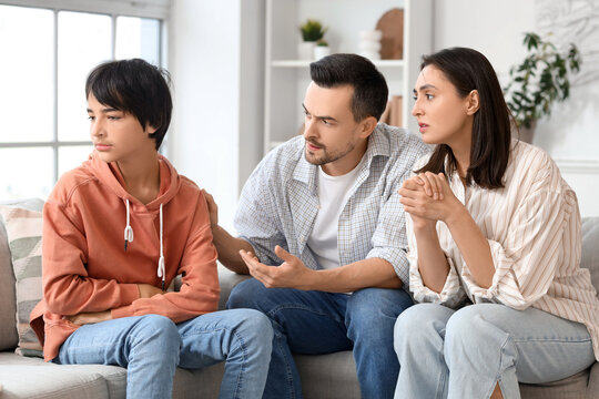 Upset teenage boy with his parents sitting at home. Family problem concept