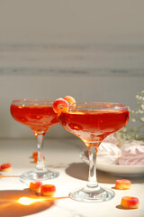 Glasses of tasty cocktail with sweets on light table, closeup. Valentine's Day celebration