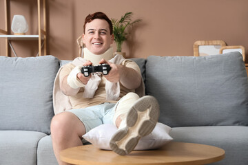 Injured young man after accident playing video game on sofa at home