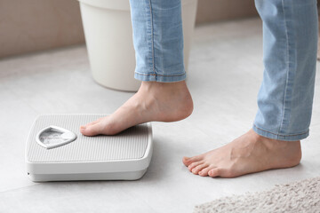 Young woman measuring her weight at home. Diet concept