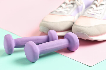 Dumbbells and sportive shoes on color background, closeup - obrazy, fototapety, plakaty