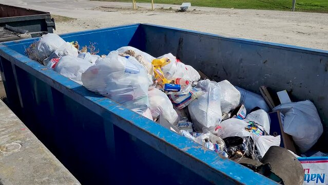 Drive up roll off dumpster filled with bagged trash and other debris
