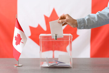Voting woman with Canadian flag near ballot box on table at polling station