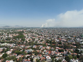 Aerial views of a sunny day in the south of CDMX, smoke in the background