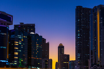 Fototapeta na wymiar Night landscape with views of the modern skyscrapers Sharjah at sunset. United Arab Emirates.