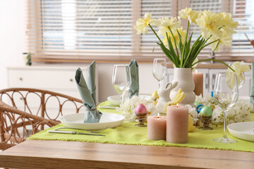 Festive table setting with vase of yellow tulips, candles and Easter bunnies