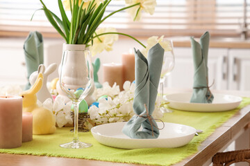 Festive table setting with vase of yellow tulips, candles and Easter bunnies