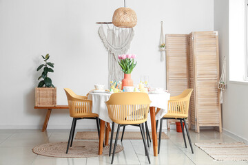 Festive table setting with vase of flowers, painted eggs and Easter bunnies in dining room