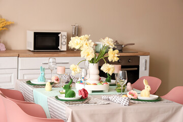 Festive table setting with vase of flowers and Easter bunnies in modern kitchen