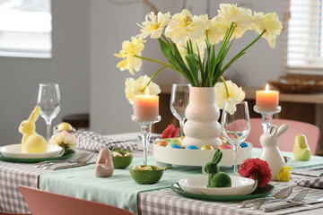 Easter table setting with vase of flowers, napkins, candles and bunnies in kitchen