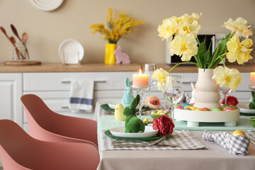 Easter table setting with vase of flowers, napkins, candles and bunnies in kitchen