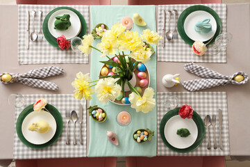 Easter table setting with vase of flowers, napkins, painted eggs and plates with Easter bunnies