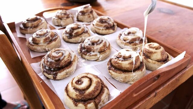 Freshly baked cinnamon buns being glazed with sugar