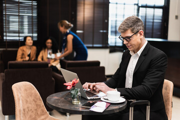 Businessman working on notebook computer and having coffee in restaurant