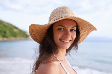 Beach, happy and portrait of woman for travel on tropical vacation, adventure or holiday. Smile, nature and female person with hat by ocean or sea water on outdoor summer weekend trip by island.